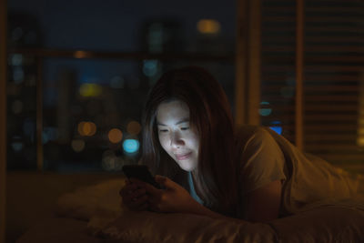 Midsection of woman using mobile phone in bed