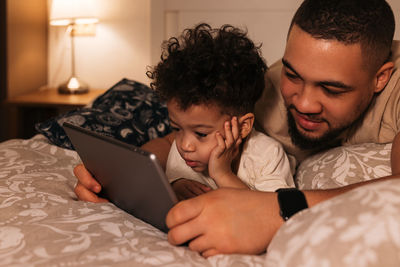 Midsection of father with baby lying on bed at home