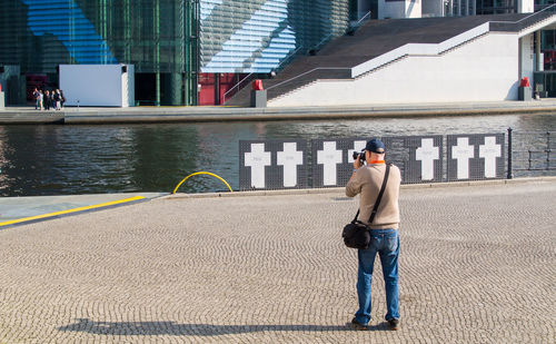 Full length of man photographing lake in city