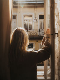 Rear view of woman standing by window