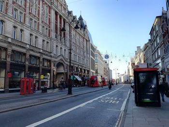 Cars on road against clear sky in city