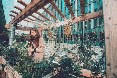 Young woman standing by plants