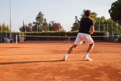 Young men playing tennis at court