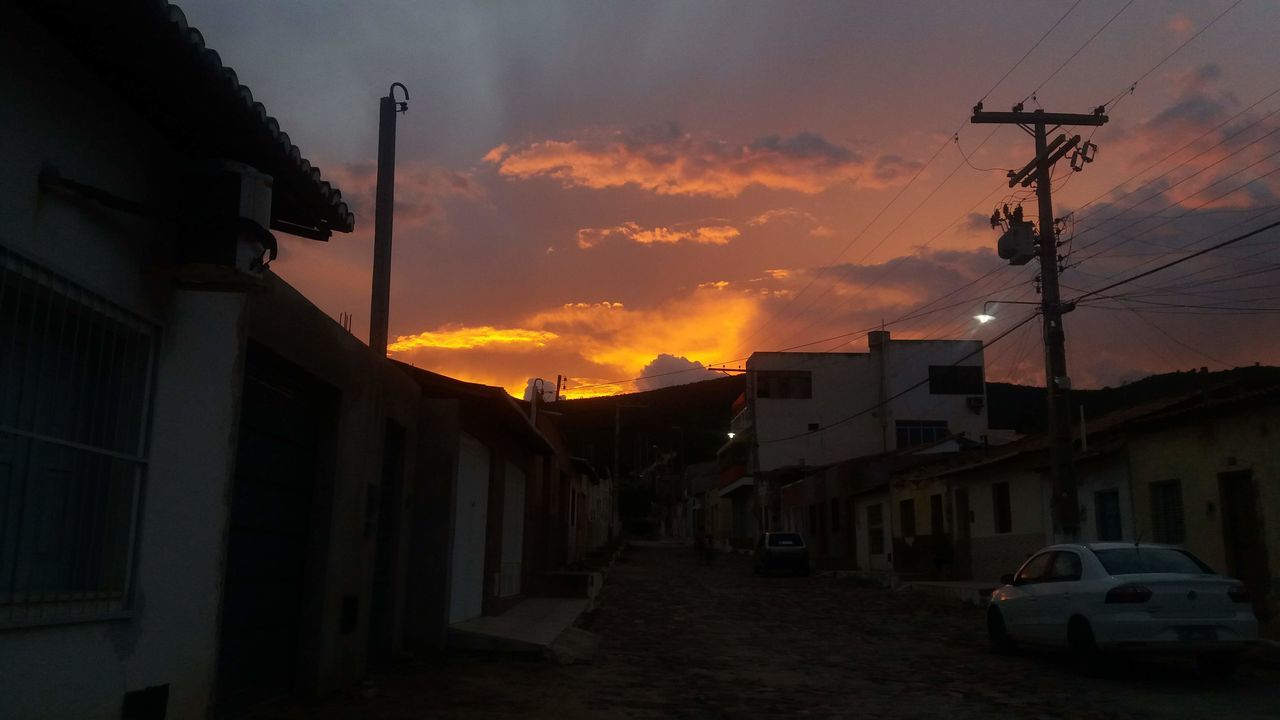 STREET AMIDST HOUSES AGAINST SKY DURING SUNSET