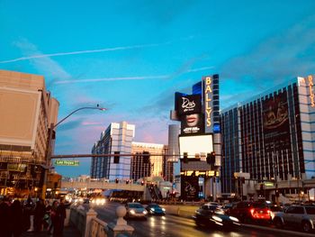 Traffic on city street by buildings against sky