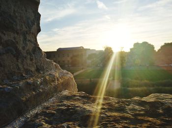 Water flowing through rocks against sky during sunset