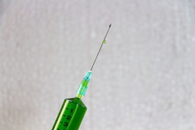Close-up of syringe against wall