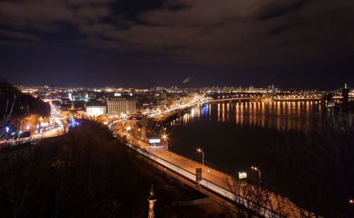 High angle view of illuminated buildings by river against sky