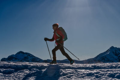 Man skiing on snowcapped mountain against sky