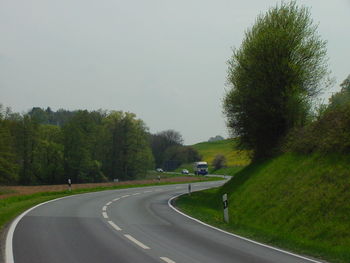 Road amidst trees against clear sky