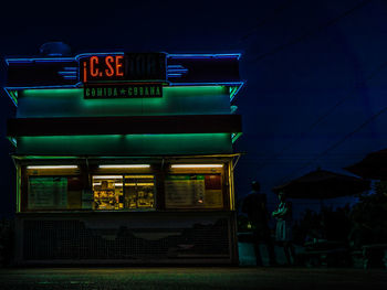 Man and woman standing by illuminated restaurant at night