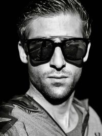 Portrait of man wearing sunglasses against black background