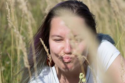 Close-up of young woman puckering by plants on field