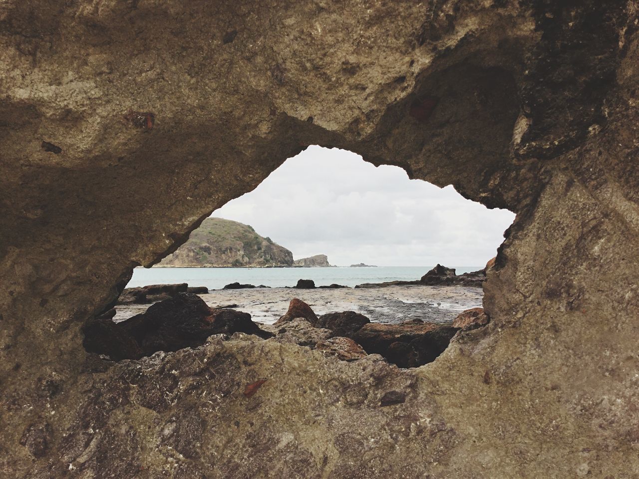 sea, water, rock - object, beach, rock formation, cave, scenics, indoors, natural arch, sky, textured, tranquil scene, tranquility, cloud - sky, shore, nature, remote, beauty in nature, non-urban scene, arch, day, cliff, archway, geology, coastline, no people