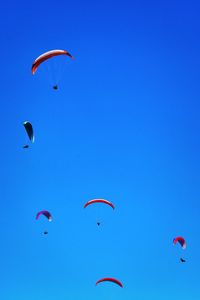 Low angle view of person paragliding against clear blue sky