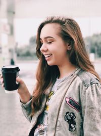 Portrait of smiling young woman holding coffee