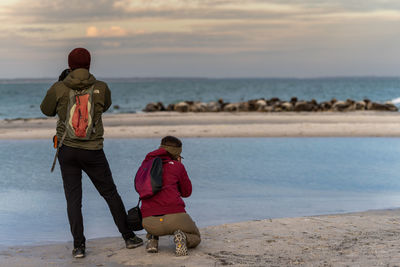 Rear view of women on beach against sky