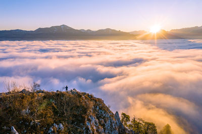 High angle view of man standing on mountain ridge rising above the clouds, hallein, austria