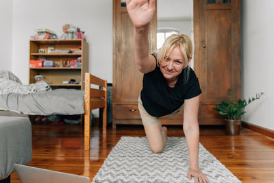 Smiling woman doing stretching exercise at home
