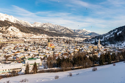 Snow covered trees and buildings against sky