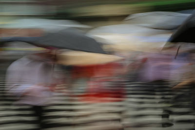 Blurred motion of people walking on street in rain