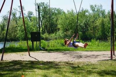 Full length of woman on swing against trees