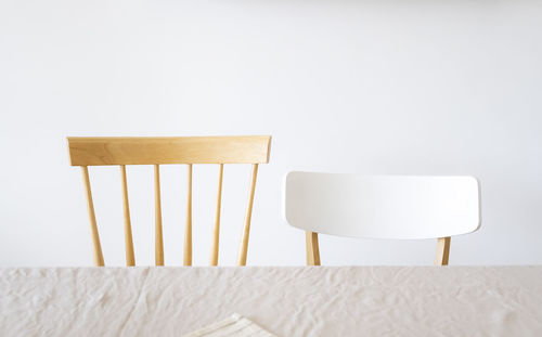 Empty chair and table against white wall at home