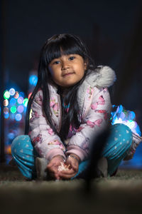 Portrait of girl sitting outdoors at night