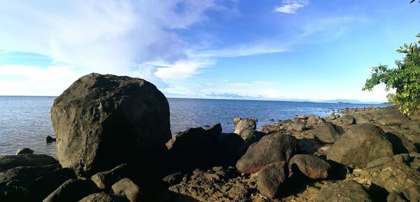 Rocks on shore by sea against sky