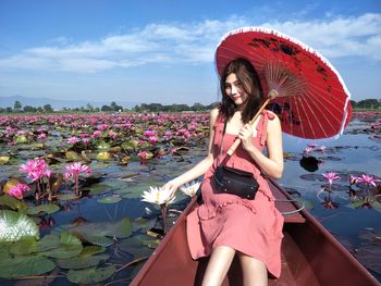 Woman with pink flowers against sky