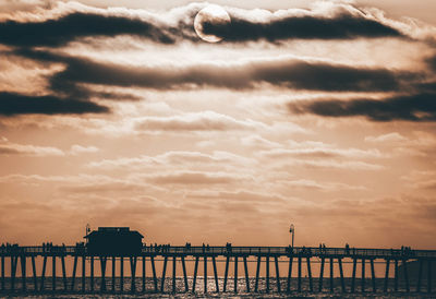 Pier over sea against sky during sunset