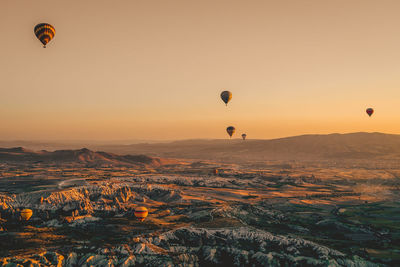 Hot air balloons flying over landscape against sky