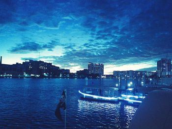 View of city at waterfront against cloudy sky