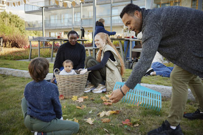 Neighbors relaxing and raking leaves in communal outdoor area