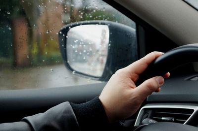 Cropped hand driving car during rainy season