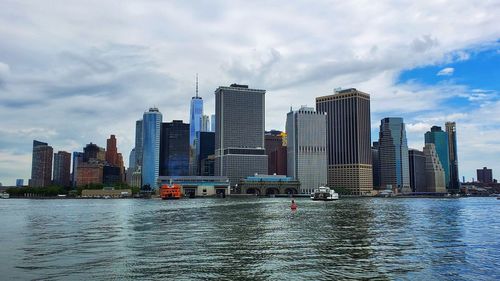 Sea by modern buildings against sky in city