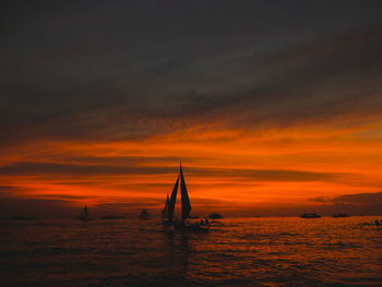 Silhouette sailboat sailing on sea against sky during sunset