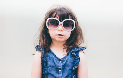 Portrait of girl wearing sunglasses against white background