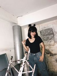 Portrait of smiling young woman standing against wall
