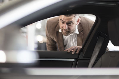 Man looking into car in car dealership