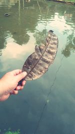 Reflection of person hand on water in lake