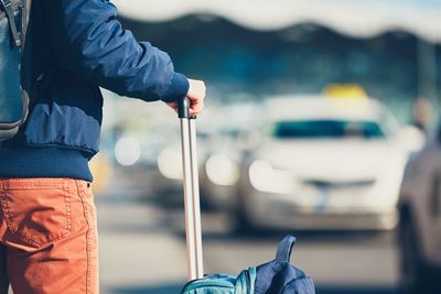 Midsection of man with luggage at taxi rank