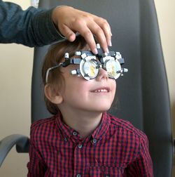 Cropped hand of ophthalmologist examining patient eye in clinic