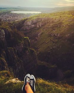 Low section of woman relaxing on cliff