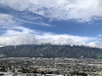 Aerial view of townscape by mountain against sky