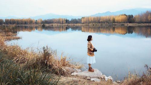 Rear view of woman on lakeshore against sky