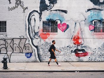 Full length of man running on sidewalk in city