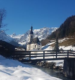 Snow covered landscape against clear blue sky