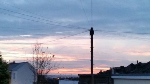 Electricity pylon against cloudy sky