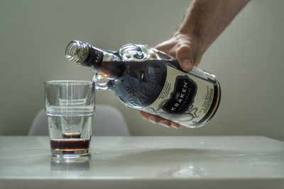 Close-up of hand pouring water in glass on table